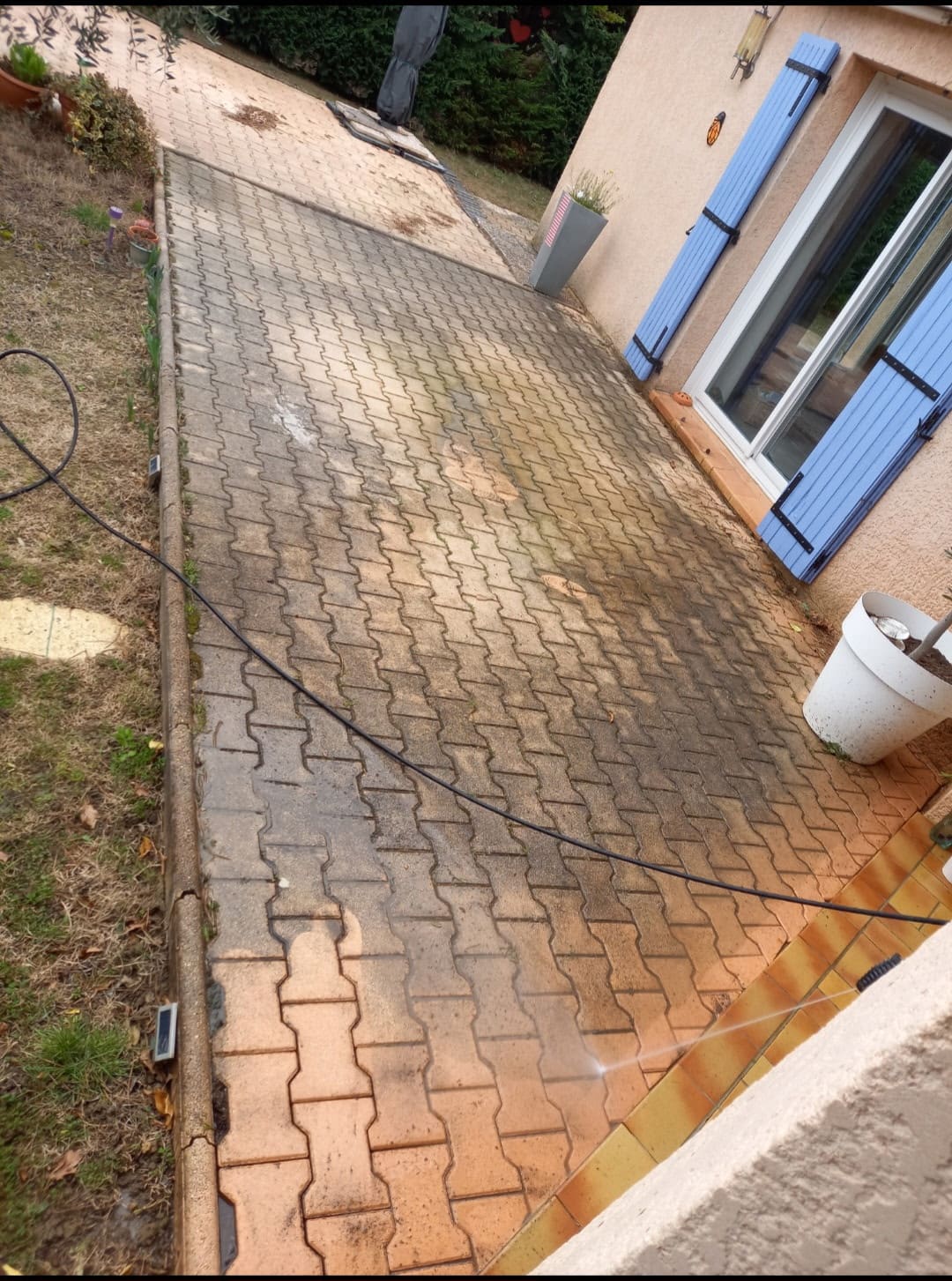 Terrasse en pavés nettoyée au jet haute pression, moitié traitée